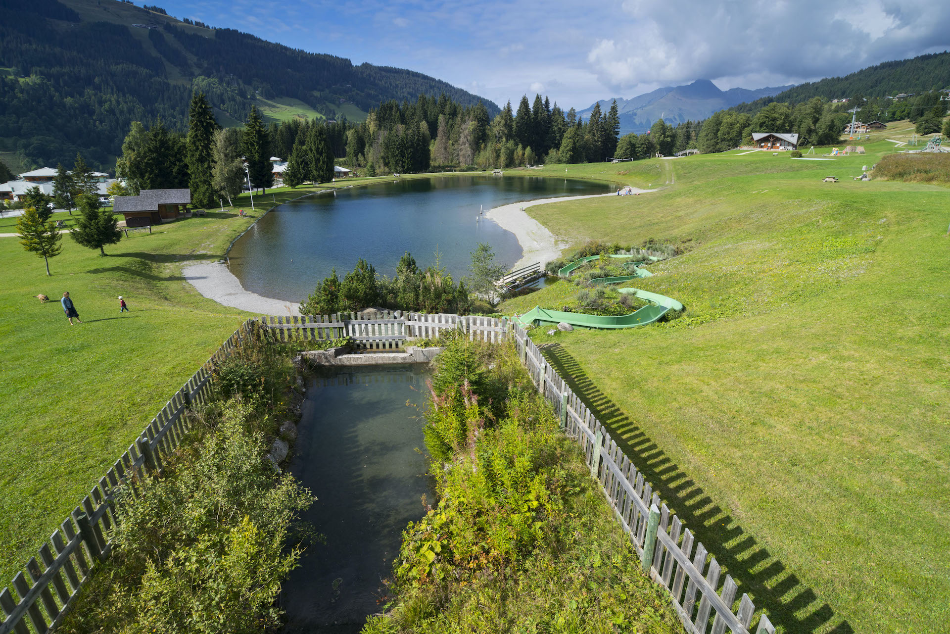 Vue d'ensemble d'un lac de montagne en été avec pelouses, toboggan et réserve d'eau