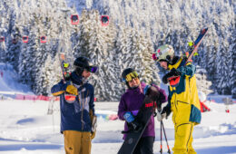 Skieurs et snowboardeuse discutant avec télécabine rouge derrière